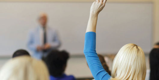 Woman with hand up in classroom