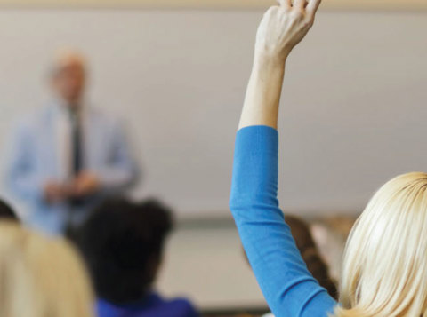 Woman with hand up in classroom