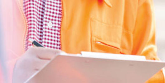 Man in orange jacket writing on a clipboard