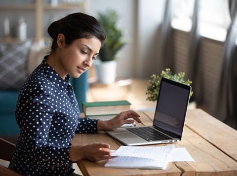 professional lady reading and using a laptop at a desk