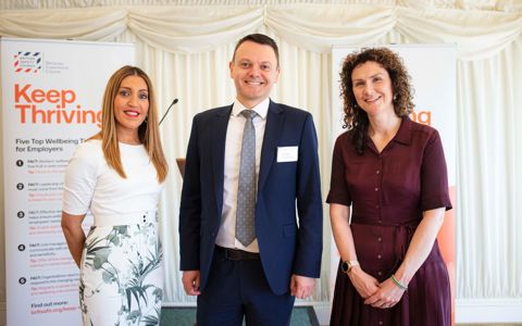 Peter McGettrick with two guests in front of Keep Thriving wellbeing campaign banners
