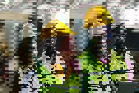 Two people wearing PPE looking at a laptop while managing a premises