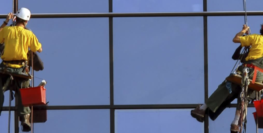 Two window cleaners working at height wearing PPE