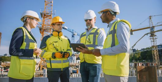 Four people wearing PPE having a conversation at a construction site