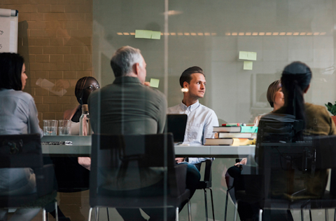 Colleagues in a meeting room discussing plans around a table