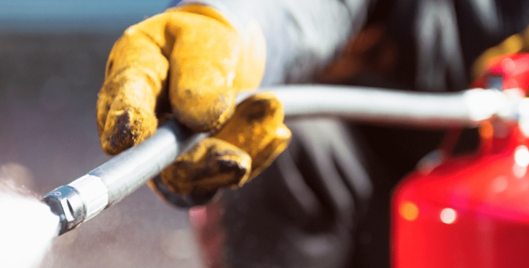Person spraying a fire extinguisher wearing yellow protective gloves